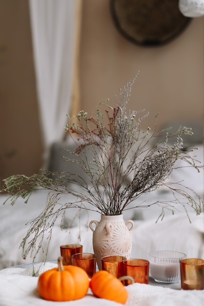 Composition d'automne avec livre de bougies citrouilles et fleurs séchées avec plaid chaud