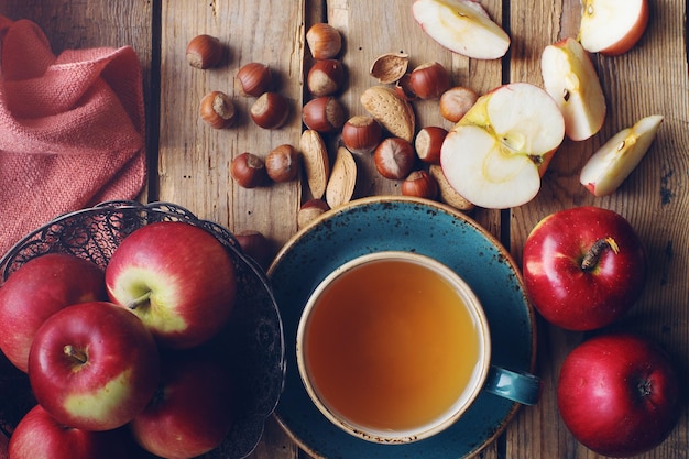 Composition d'automne matinale confortable avec une tasse de thé, des pommes fraîches et des noix sur une table en bois rustique