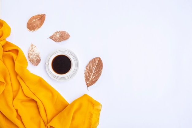 Composition d'automne. Tasse de café, écharpe jaune, feuilles sèches sur fond blanc. Automne, concept d'automne. Mise à plat, vue de dessus, espace de copie