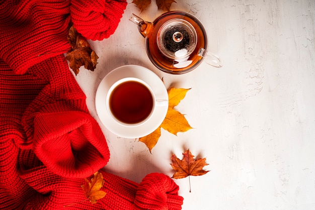 Composition d'automne. Une tasse de thé et une théière, un pull rouge, des feuilles d'automne. Mise à plat, vue de dessus, espace de copie. photo de haute qualité