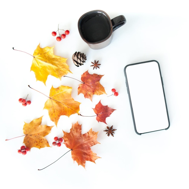 Composition d'automne avec un téléphone un verre et des feuilles d'automne sur fond blanc à plat