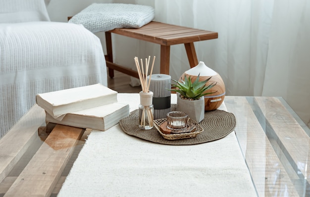 Composition avec bâtons d'encens, diffuseur, bougies et livres sur la table à l'intérieur de la pièce.