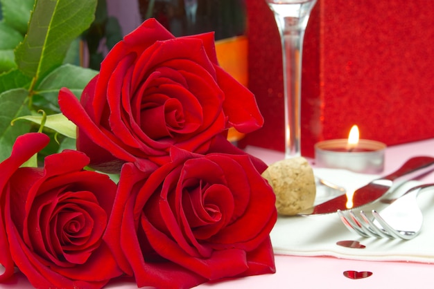 Une composition d'un beau bouquet de roses, de verres et d'une bouteille de champagne crée une carte ou une affiche romantique. Le concept de la Saint-Valentin, fête des mères, 8 mars.