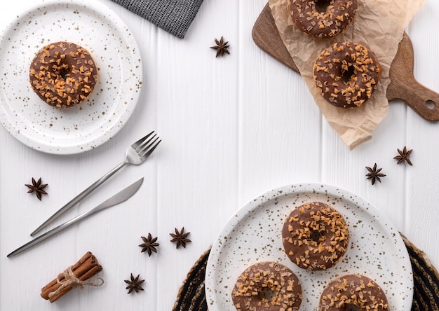 Composition avec des beignets glacés sur une plaque sur une table en bois blanc.