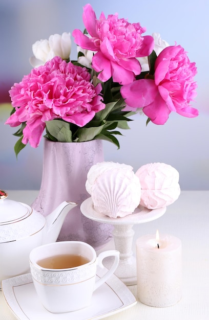 Composition De Belles Pivoines En Vase, Thé En Tasse Et Guimauve, Sur Table, Sur Fond Clair