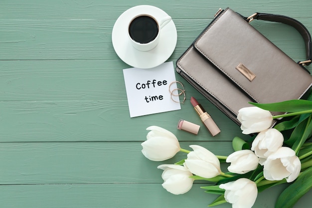 Composition avec de belles tulipes, accessoires féminins et tasse de café sur une table en bois de couleur '