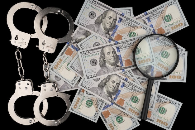 composition d'un billet de 100 dollars sur fond noir et des menottes de police