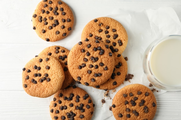 Composition avec biscuits aux pépites et lait sur une table en bois blanc