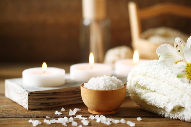 Composition de bougies de traitement spa dans un bol avec de l'eau sur fond de bois
