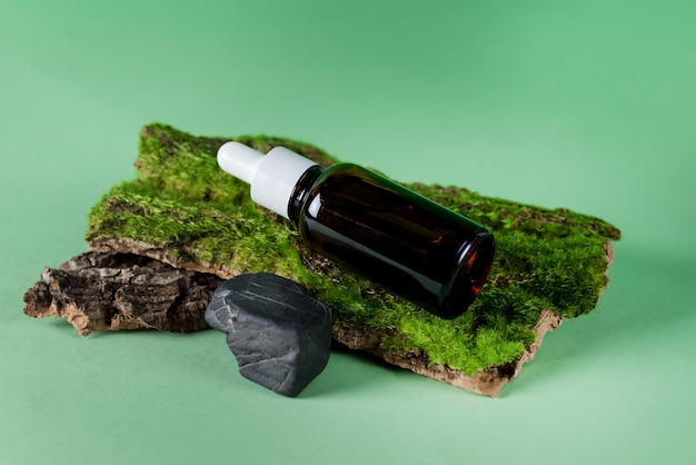 Composition avec bouteille d'huile essentielle ou de sérum sur l'écorce d'arbre avec Moss Beauty and SPA Concept