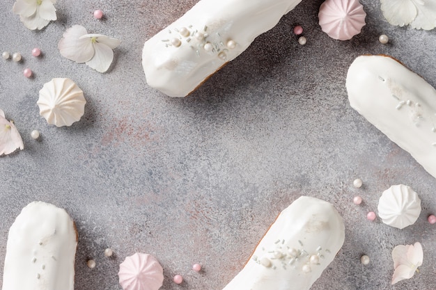 Composition de cadre avec éclairs de glaçure blanche, bonbons, fleurs sur fond de béton. Concept de vacances créatives avec espace pour le texte. Modèle plat