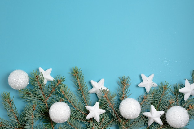 Composition de cadre de Noël de branches de sapin, coffrets cadeaux bleus, boules blanches.