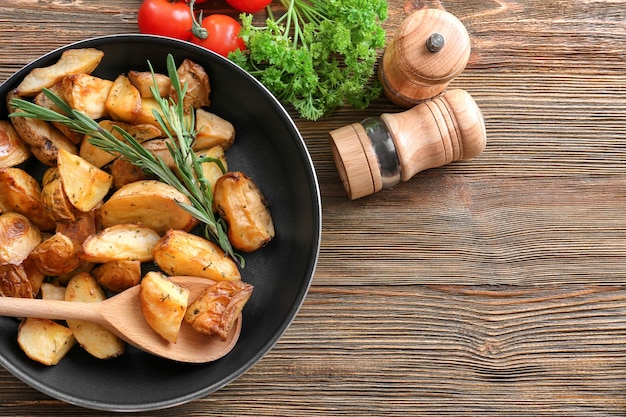 Composition avec casserole de pommes de terre au romarin cuites sur table en bois