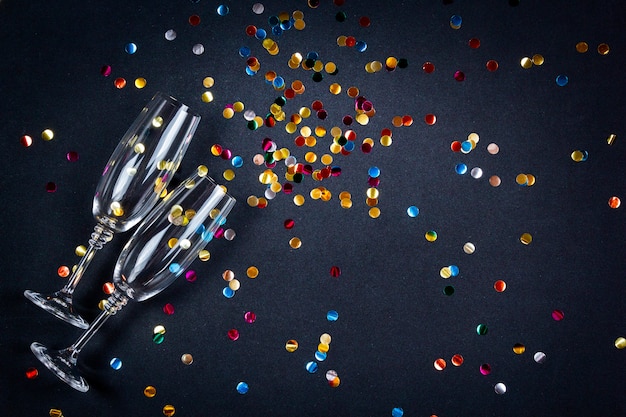 Composition de célébration avec des verres de vin de champagne et des confettis sur une surface festive