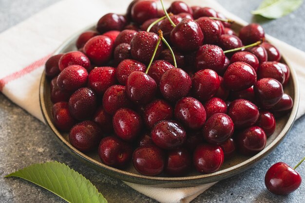 Composition de cerises douces sur une assiette avec des gouttes d'eau Concept d'été et de récolte Macro de cerise Aliments crus végétariens végétaliens