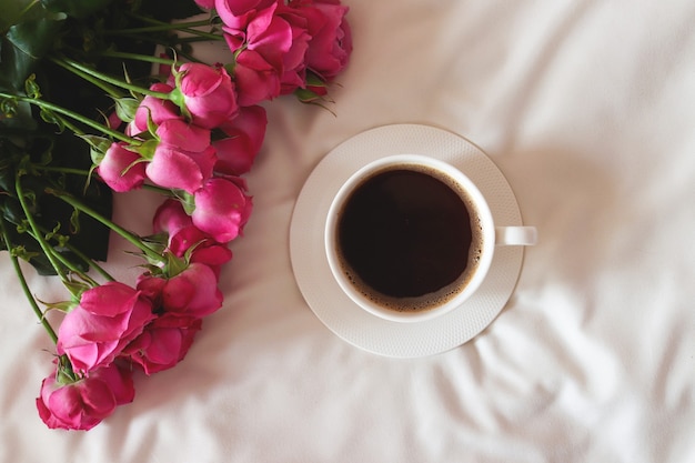 Composition chaleureuse matinée à plat avec des fleurs et une tasse de café Petit-déjeuner au lit