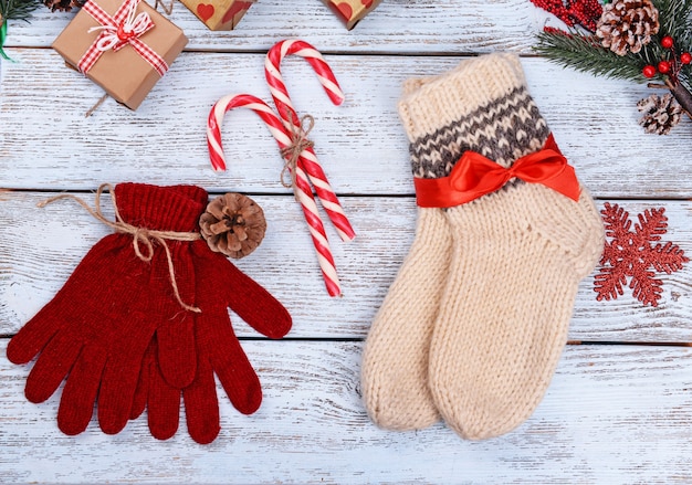 Composition de chaussettes chaudes et de gants avec des décorations de Noël sur fond de bois blanc