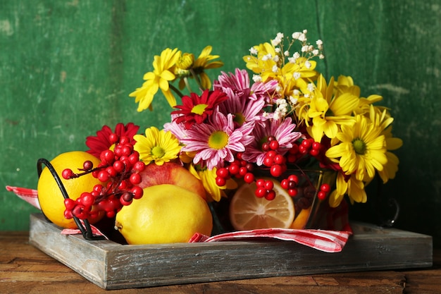 Composition avec chrysanthème et fruits sur bois