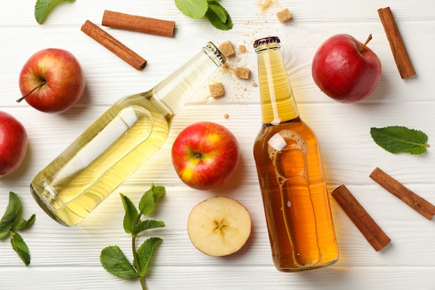 Composition avec cidre, cannelle et pommes sur table en bois blanc