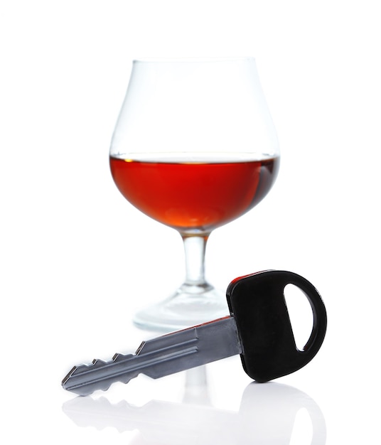 Composition avec clé de voiture et verre de cognac isolé sur blanc