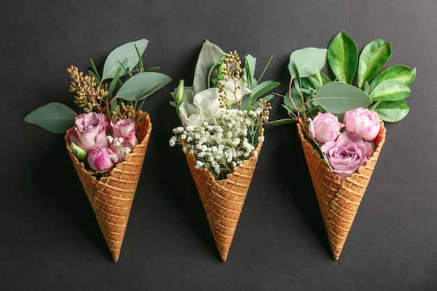 Composition de cônes gaufrés avec fleurs et branches sur fond sombre