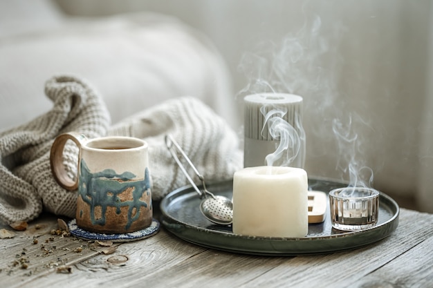 Composition Confortable Avec Une Tasse En Céramique, Des Bougies Et Un élément Tricoté Sur Fond Flou.