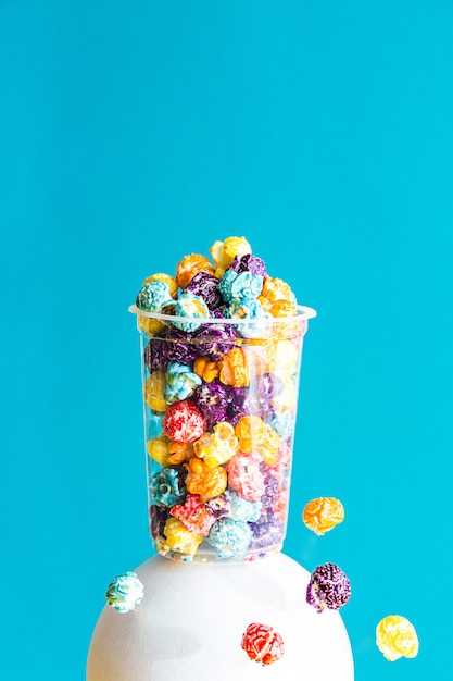 Composition créative avec du pop-corn coloré dans un verre transparent