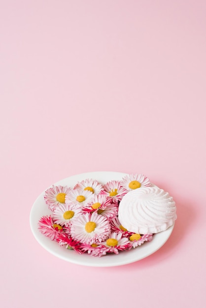 Composition créative Fleurs marguerites et guimauves sur une assiette avec espace de copie