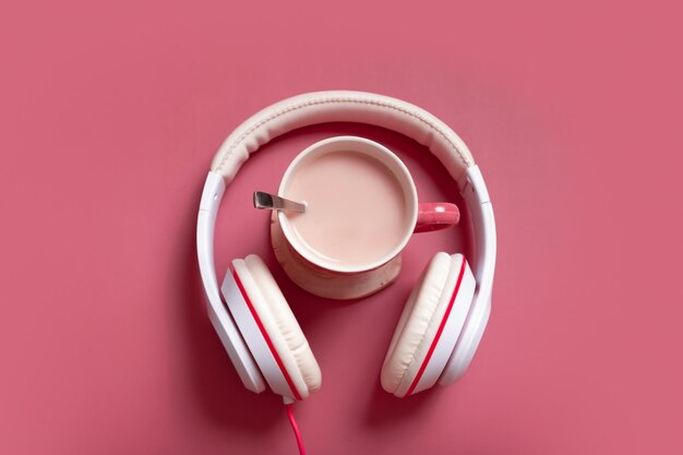 Composition créative à plat avec tasse de cacao et écouteurs sur fond de couleur rose foncé Musique créative relax concept en ligne