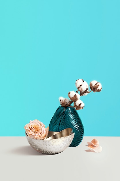 Composition créative avec vase, fleur et coton décoratif sur une table grise sur fond bleu avec un espace pour la conception. Concept de magasin de fleurs. Décoration minimalisme