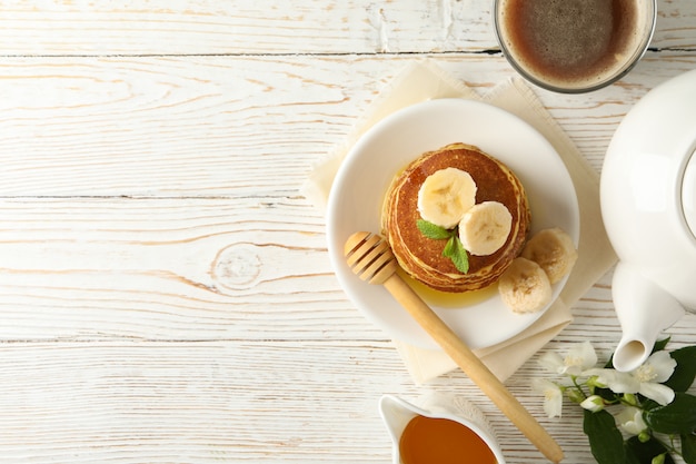 Composition avec crêpes sur table en bois blanc, vue de dessus. Petit déjeuner sucré