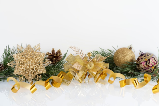 Composition de décoration de Noël boules d'or, flocon de neige, cloches et cônes avec des branches de pin sur blanc