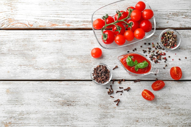 Composition avec une délicieuse sauce tomate et épices sur table en bois