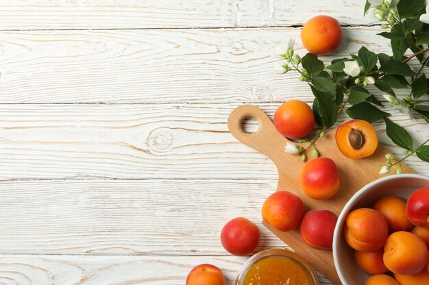 Composition avec de délicieux abricots et confiture sur table en bois blanc