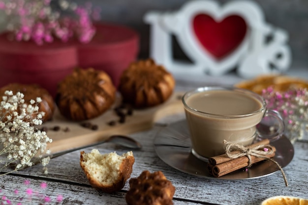 Composition de délicieux muffins faits maison pour le petit-déjeuner festif et une tasse de café au lait sur un fond clair en bois de fleurs et un gros plan de boîte rouge