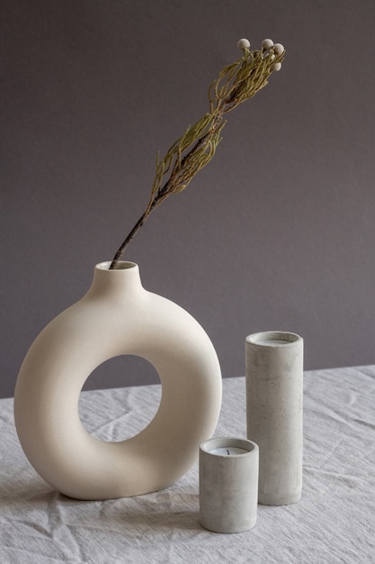 Composition de deux bougies soufflées aromatiques dans des verres en céramique blanche debout sur la table par vase fait main créatif avec des fleurs séchées