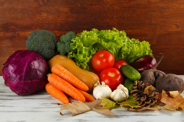 Composition de différents légumes avec des feuilles jaunes sur table sur fond de bois