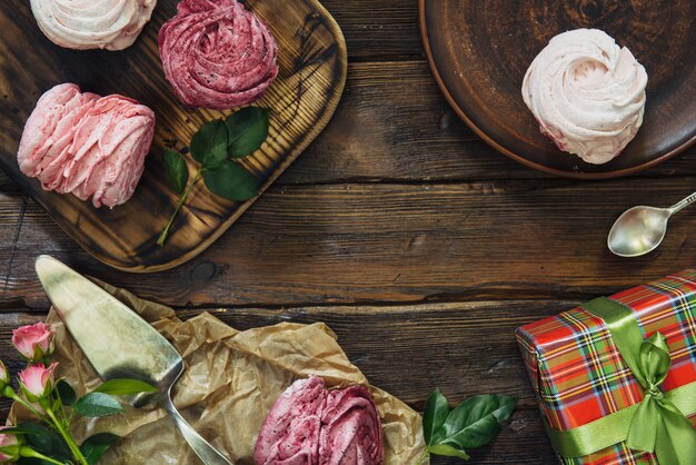 Composition de diverses meringues de bleuets, cerises et fleurs sur une surface en bois sombre