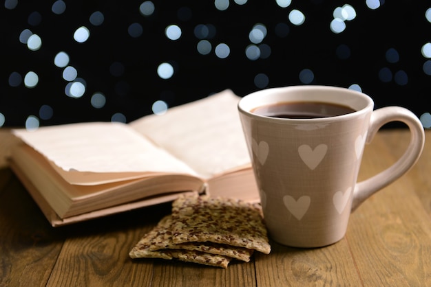 Composition du livre avec une tasse de café sur la table sur fond sombre