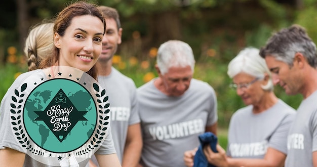 Composition du logo du globe vert et du texte du jour de la terre sur des volontaires nettoyant la campagne