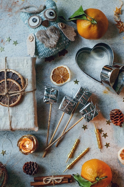 Composition du Nouvel An ou de Noël avec des mandarines, des oranges sèches, de la cannelle, des cadeaux, des bonbons et des jouets sur une table rustique légère