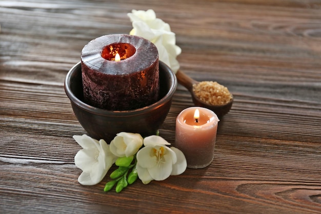 Composition du spa avec des bougies allumées et de belles fleurs sur fond de bois