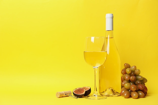 Composition avec du vin et des fruits sur fond jaune