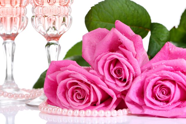 Composition avec du vin mousseux rose dans des verres et des roses roses isolées sur blanc