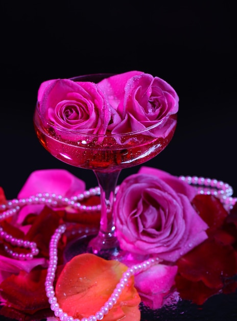 Composition avec du vin mousseux rose et des roses en verre, isolées sur fond noir