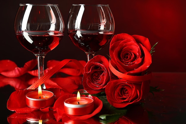 Composition avec du vin rouge dans des verres, une rose rouge et un coeur décoratif sur fond coloré