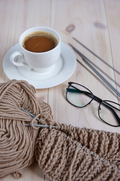 Composition d'un écheveau de fil, verres, une tasse de café sur un fond en bois clair