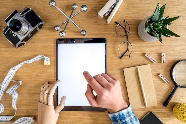 Composition élégante de bureau à domicile d'un écran de tablette maquette, de fournitures de bureau, d'une tasse de café, d'un téléphone, d'un appareil photo, de plantes et d'accessoires personnels dans le concept d'entreprise.