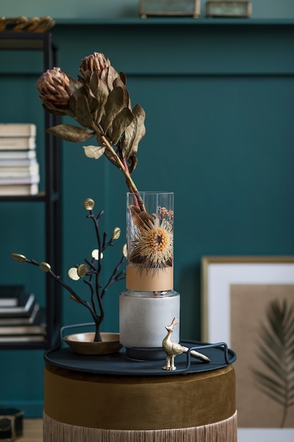 Composition élégante et florale de belles fleurs dans des vases modernes sur l'étagère design avec des accessoires élégants. Concept de fleur avec des ombres sur le mur beige. Aménagement intérieur..