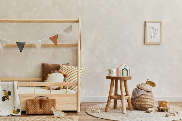 Composition élégante de l'intérieur de la chambre d'enfant scandinave confortable avec lit en bois, jouets et décorations suspendues. Mur créatif. Espace de copie. Modèle.